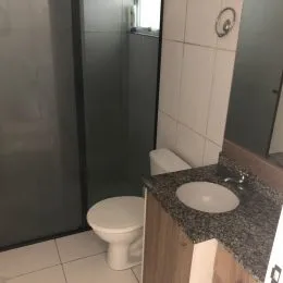 Foto de um banheiro mostrando um vaso sanitário e azulejos brancos.