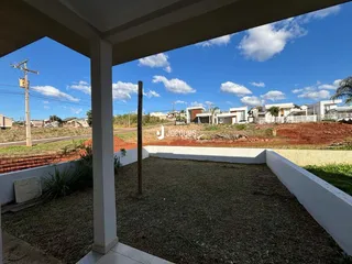 Lote de terra com cerca branca e grama seca no quintal.