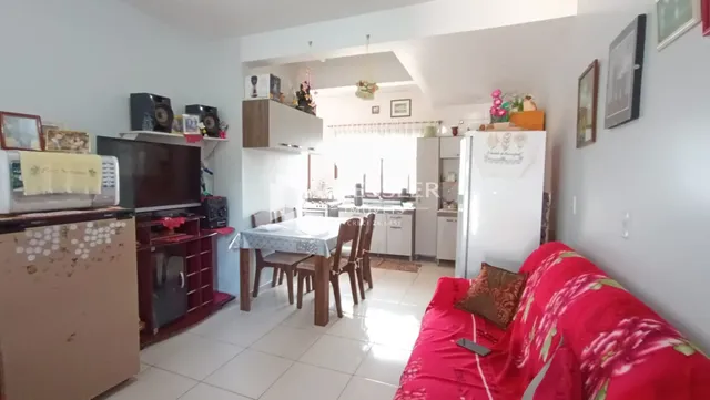 Sala de estar com mesa de jantar e sofá vermelho em um imóvel no Brasil.