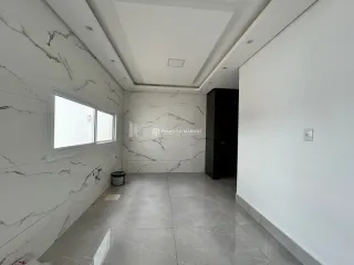 Hall de corredor com paredes brancas e piso de mármore claro.