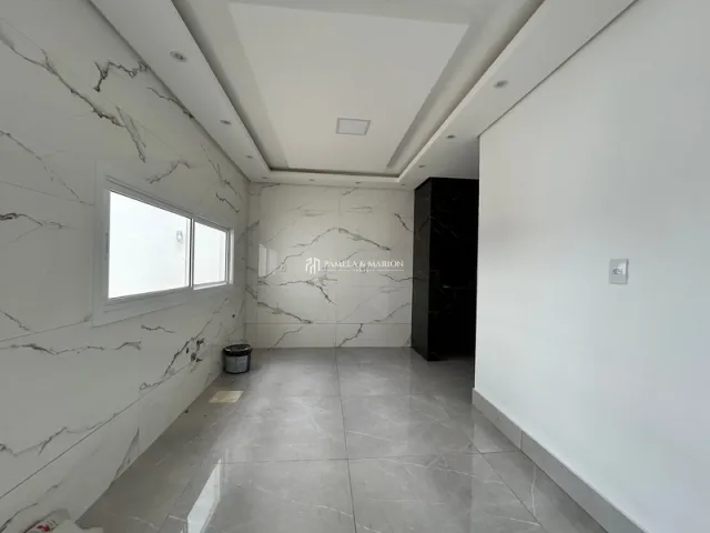 Hall de corredor com paredes brancas e piso de mármore claro.