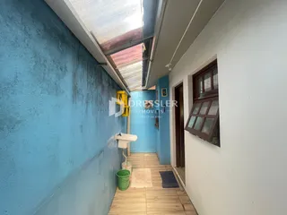 Foto de um corredor interno com paredes azuis e piso de madeira em uma residência.