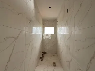 Corredor interno com revestimento de mármore branco nas paredes.