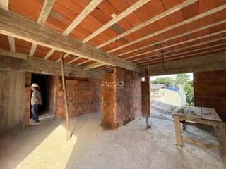 Vista interna de uma estrutura em construção com paredes de tijolo aparente.