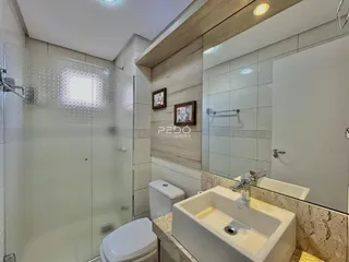 Imagem de um banheiro moderno com box de vidro e louças brancas.