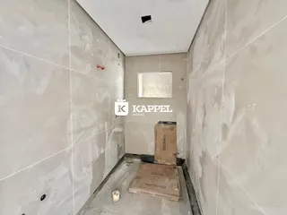 Este é um corredor interno com paredes claras e uma janela no final.