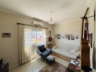 Sala de estar clara com janela e cortinas brancas.