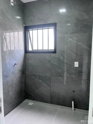 Foto de um corredor interno com paredes cinzas e uma janela grande.