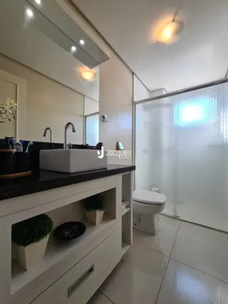 Banheiro moderno com bancada escura e piso claro.