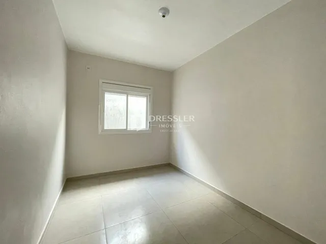 Interior de um cômodo com paredes brancas e piso de cerâmica.
