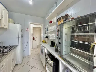 Vista de uma cozinha com armários brancos e eletrodomésticos em Lajeado.