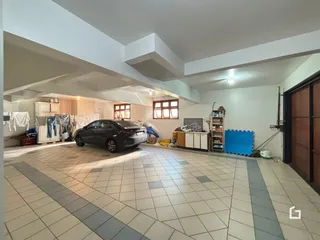 Vista interna de uma área ampla com piso de cerâmica e um carro estacionado.