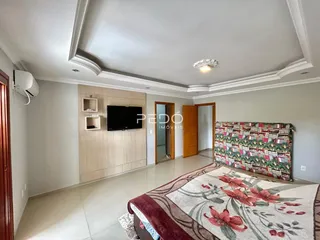 Ambiente interno de uma sala com cabeceira e televisão montada na parede.