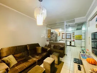 Foto da sala de estar com um sofá marrom e pufes.