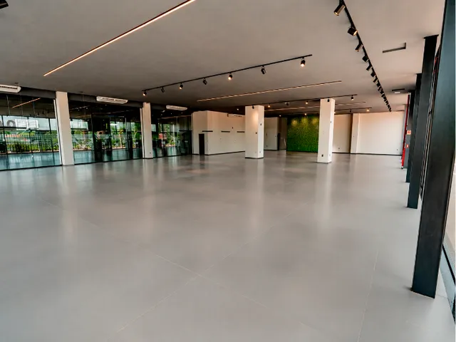 Espaço interno amplo com piso claro e teto alto.