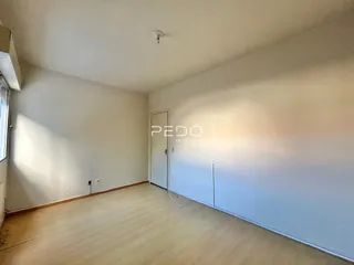Ambiente interno de uma sala vazia com piso de madeira clara.