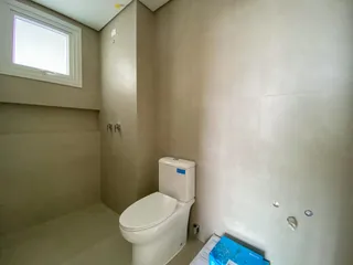 Foto de um banheiro interno mostrando um vaso sanitário branco e paredes neutras.