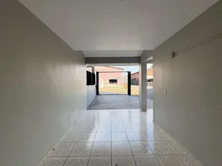 Corredor interno com piso de cerâmica claro e paredes brancas.