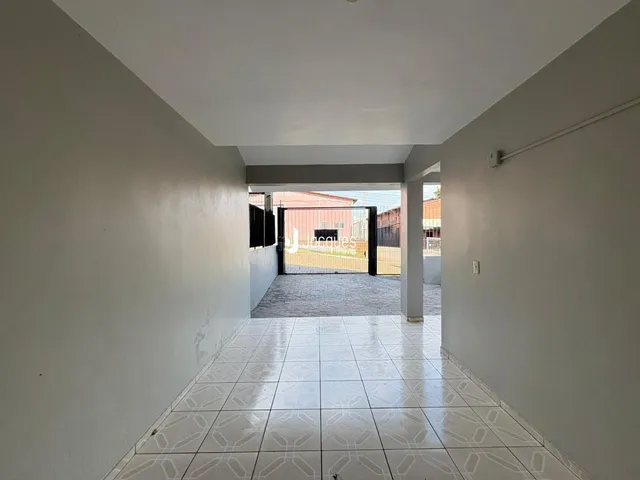 Corredor interno com piso de cerâmica claro e paredes brancas.