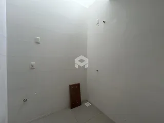 Foto de um corredor interno com paredes brancas e piso claro.