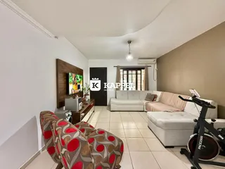 Sala de estar com sofá estampado e televisão montada na parede.