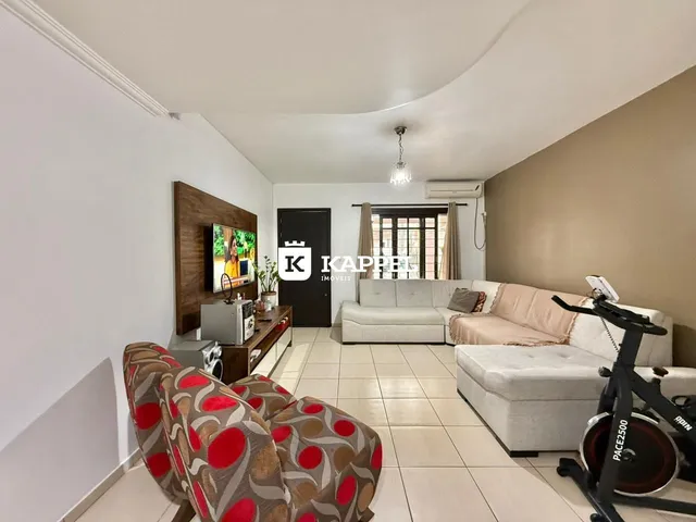 Sala de estar com sofá estampado e televisão montada na parede.