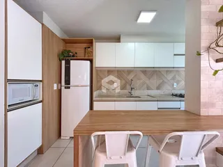 Cozinha moderna com armários brancos e bancada clara.