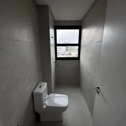 Foto de um banheiro simples mostrando um vaso sanitário em um corredor.