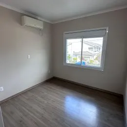 Foto de um cômodo interno com piso de madeira e uma janela.
