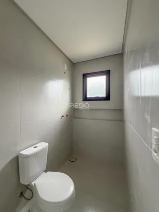 Banheiro com revestimento claro e janela.