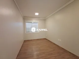 Vista interna de um cômodo com piso de madeira e paredes claras.