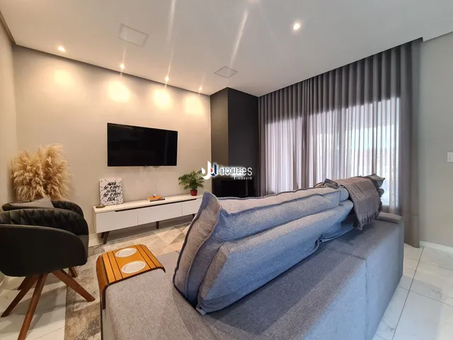Sala de estar moderna com sofá cinza e televisão em um apartamento.