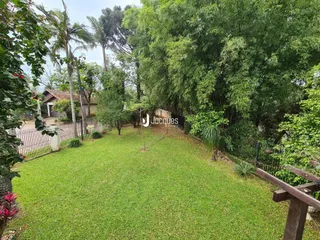 Vista de um gramado verde com árvores e cerca em uma propriedade em Lajeado.
