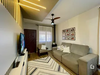 Sala de estar com sofá cinza e piso de madeira clara.