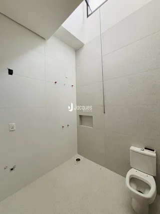Foto de um banheiro com paredes brancas e piso claro.
