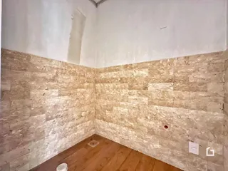Parede interna com revestimento de pedra e piso de madeira.