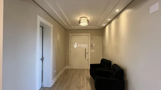 Corredor interno com piso de madeira e paredes brancas.