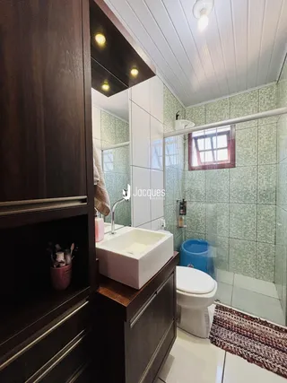 Banheiro com box de vidro e revestimento cerâmico nas paredes.