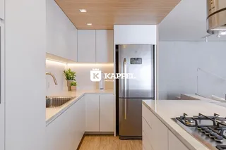 Cozinha moderna com armários brancos e eletrodomésticos de aço inoxidável.
