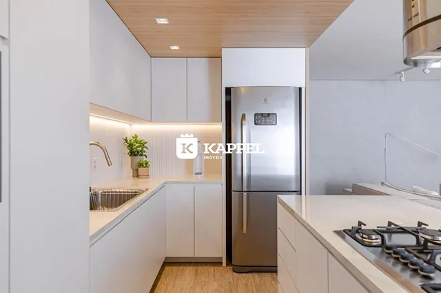 Cozinha moderna com armários brancos e eletrodomésticos de aço inoxidável.