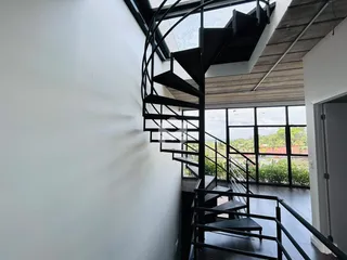 Vista de um interior com escadaria de ferro e grandes janelas.