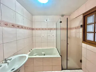 Foto de um banheiro com banheira e box de vidro em um imóvel.