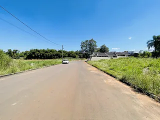 Uma estrada asfaltada se estende por uma área com vegetação ao longo de uma paisagem rural.