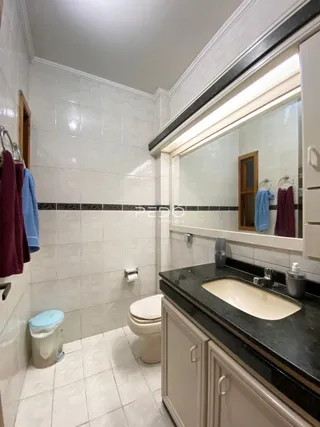 Foto de um banheiro com revestimento cerâmico branco.