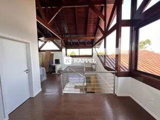 Hall de entrada com piso de madeira e estrutura de vigas expostas.