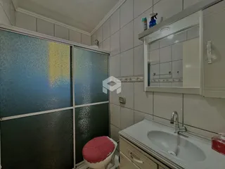 Foto de um banheiro com revestimento cerâmico e box de vidro.