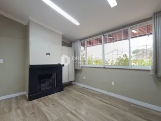 Ambiente interno de uma sala com piso de madeira e janela grande.