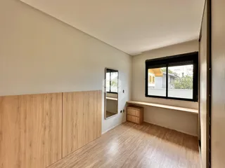 Vista interna de um ambiente com piso de madeira clara e armário embutido.
