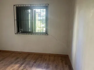 Foto de uma janela com grade preta em um ambiente interno com piso de madeira.