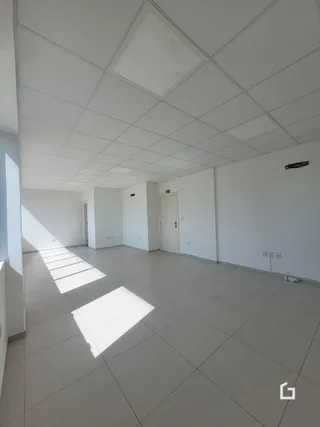 Interior amplo e iluminado com piso claro e teto branco.